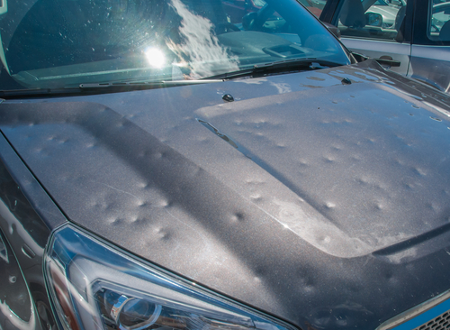 Vehicle hood with extensive hail damage showing multiple dents, highlighting the need for professional repair services at 360 Collision in San Antonio, TX.