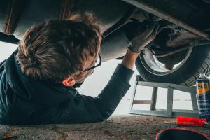 Mechanic inspecting vehicle frame and undercarriage for damage and misalignment, emphasizing the importance of frame repair services at 360 Collision.