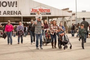 Families walking near the entrance of the San Antonio Stock Show & Rodeo, with children and strollers, showcasing a lively atmosphere of the event.