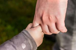 Adult and child holding hands, symbolizing family bonding and care at the San Antonio Stock Show & Rodeo.