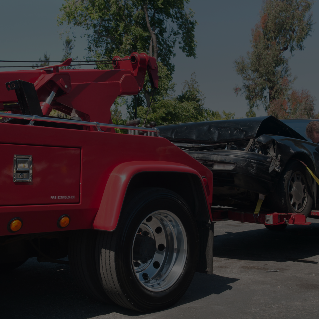 Red tow truck lifting a damaged black car, emphasizing 360 Collision's auto body repair services and accident response in San Antonio.