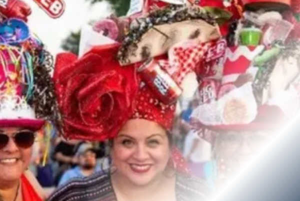 Women wearing elaborate, colorful hats adorned with festive decorations at a San Antonio festival, celebrating local culture and creativity.